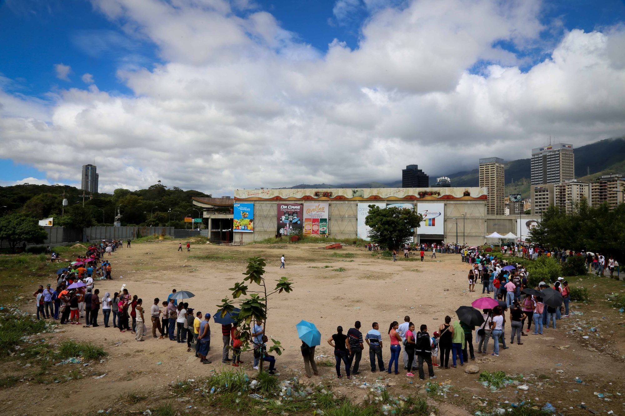 Lines of people wait to buy basic foods at a supermarket.
